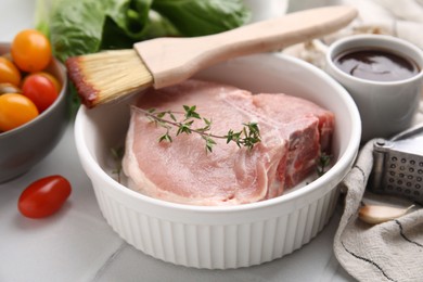 Photo of Raw meat, thyme, brush with marinade and products on light table, closeup
