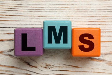 Learning management system. Colorful cubes with abbreviation LMS on wooden background, top view