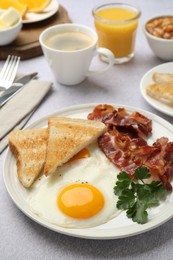 Delicious breakfast with sunny side up egg served on light table, closeup