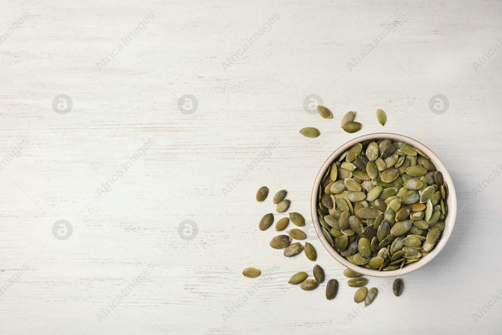 Photo of Shelled raw pumpkin seeds on wooden background, top view. Space for text