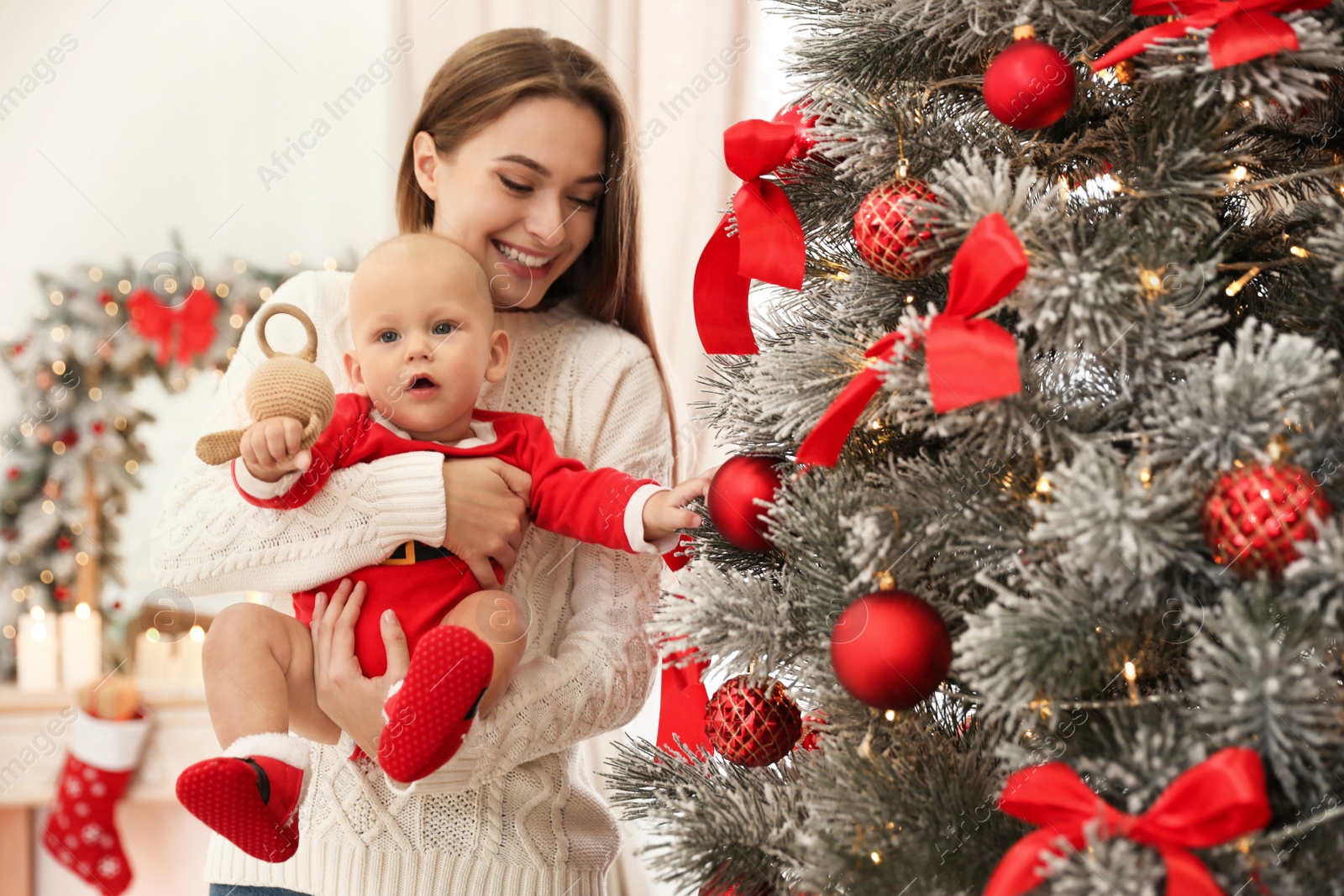 Photo of Happy mother with cute baby near Christmas tree at home