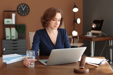 Female lawyer working with laptop at table in office