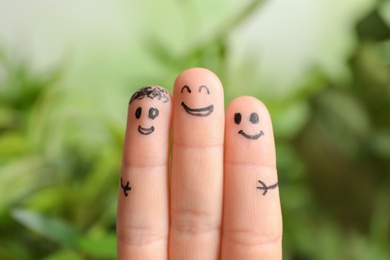 Photo of Fingers with drawings of happy faces against blurred background. Unity concept