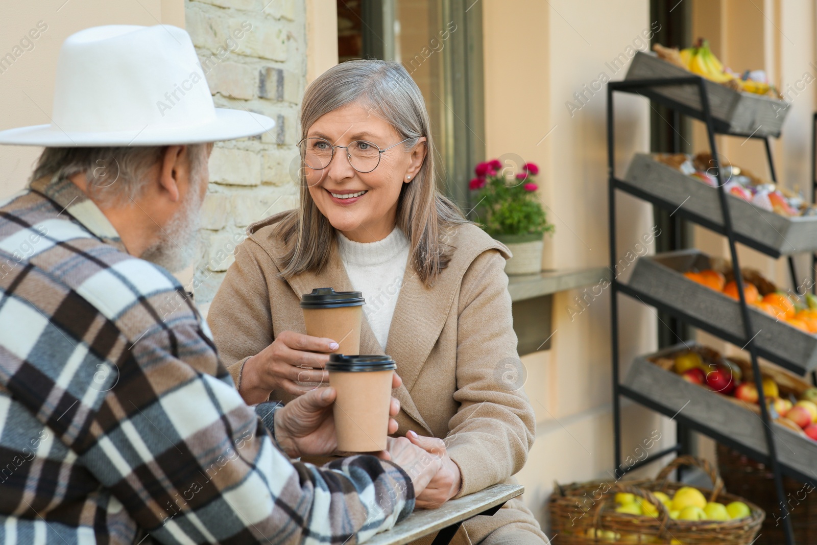 Photo of Affectionate senior couple sitting in outdoor cafe and drinking coffee, space for text