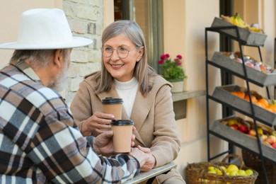Photo of Affectionate senior couple sitting in outdoor cafe and drinking coffee, space for text