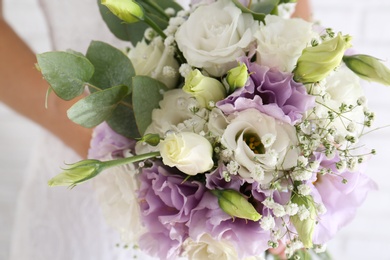 Photo of Bride holding beautiful bouquet with Eustoma flowers, closeup