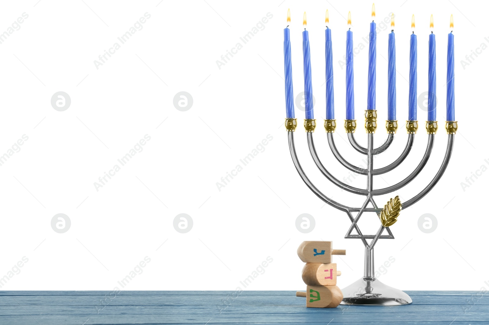 Photo of Hanukkah celebration. Menorah and dreidels on blue wooden table against white background