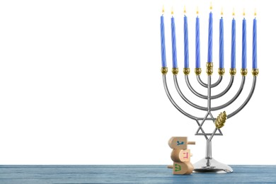 Hanukkah celebration. Menorah and dreidels on blue wooden table against white background