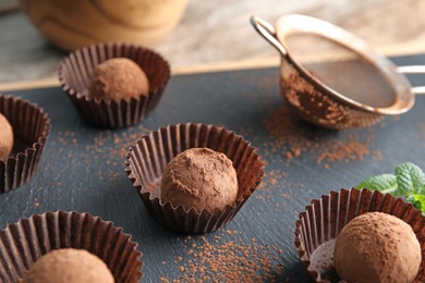 Tasty chocolate truffles on board, closeup view