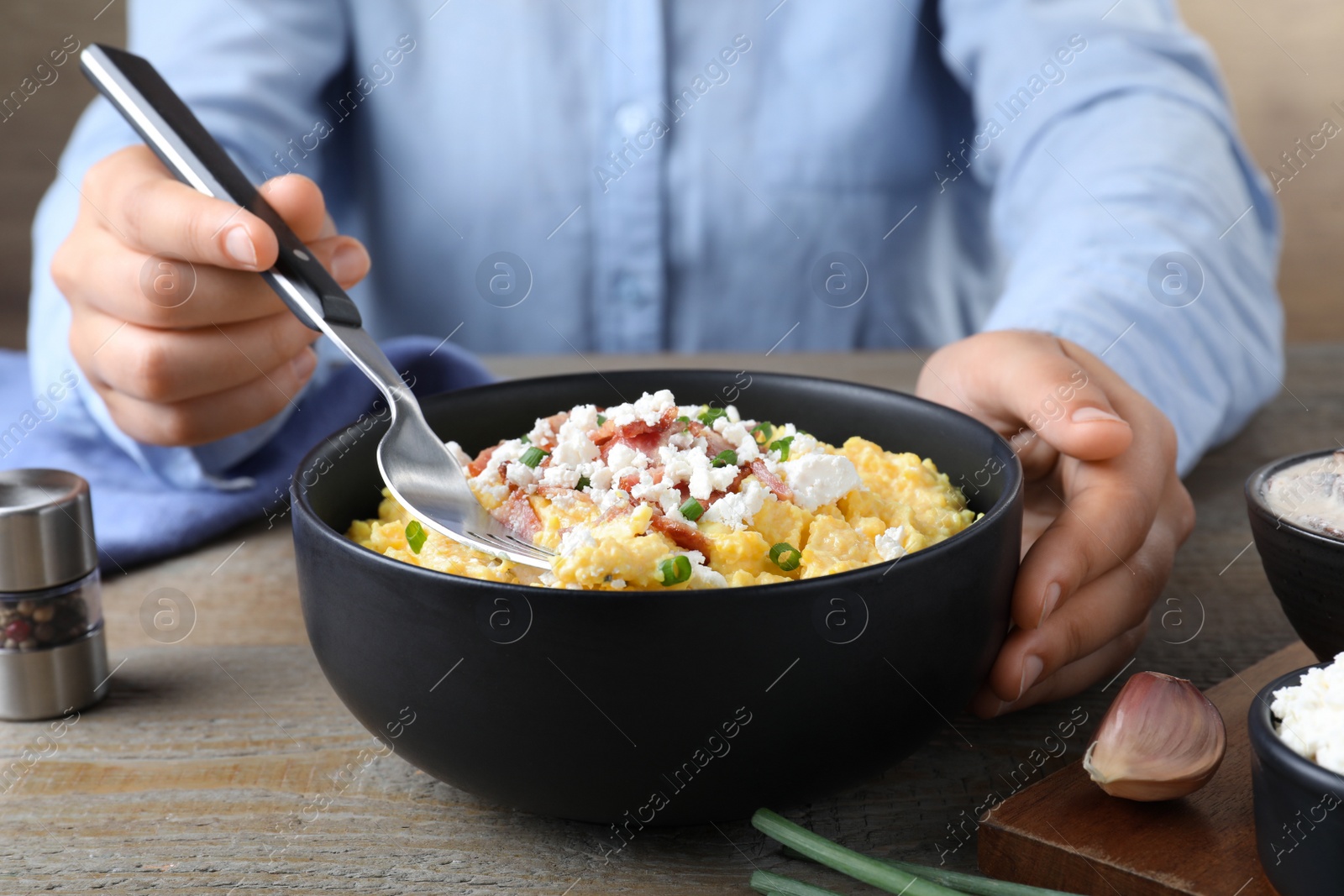 Photo of Woman eating traditional banosh at wooden table, closeup