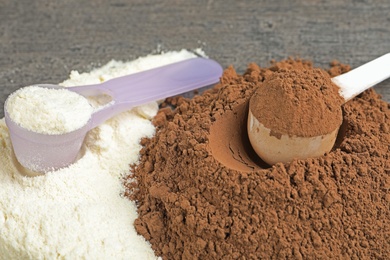 Photo of Piles of different protein powders and scoops on grey table, closeup