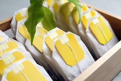 Photo of Wooden box with paper tea bags on table, closeup