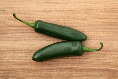 Fresh green jalapeno peppers on wooden table, flat lay