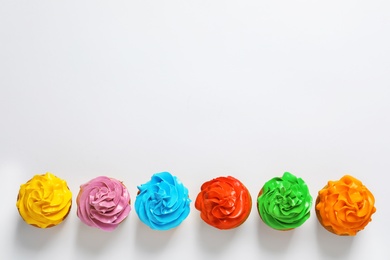 Photo of Flat lay composition with colorful birthday cupcakes on light background