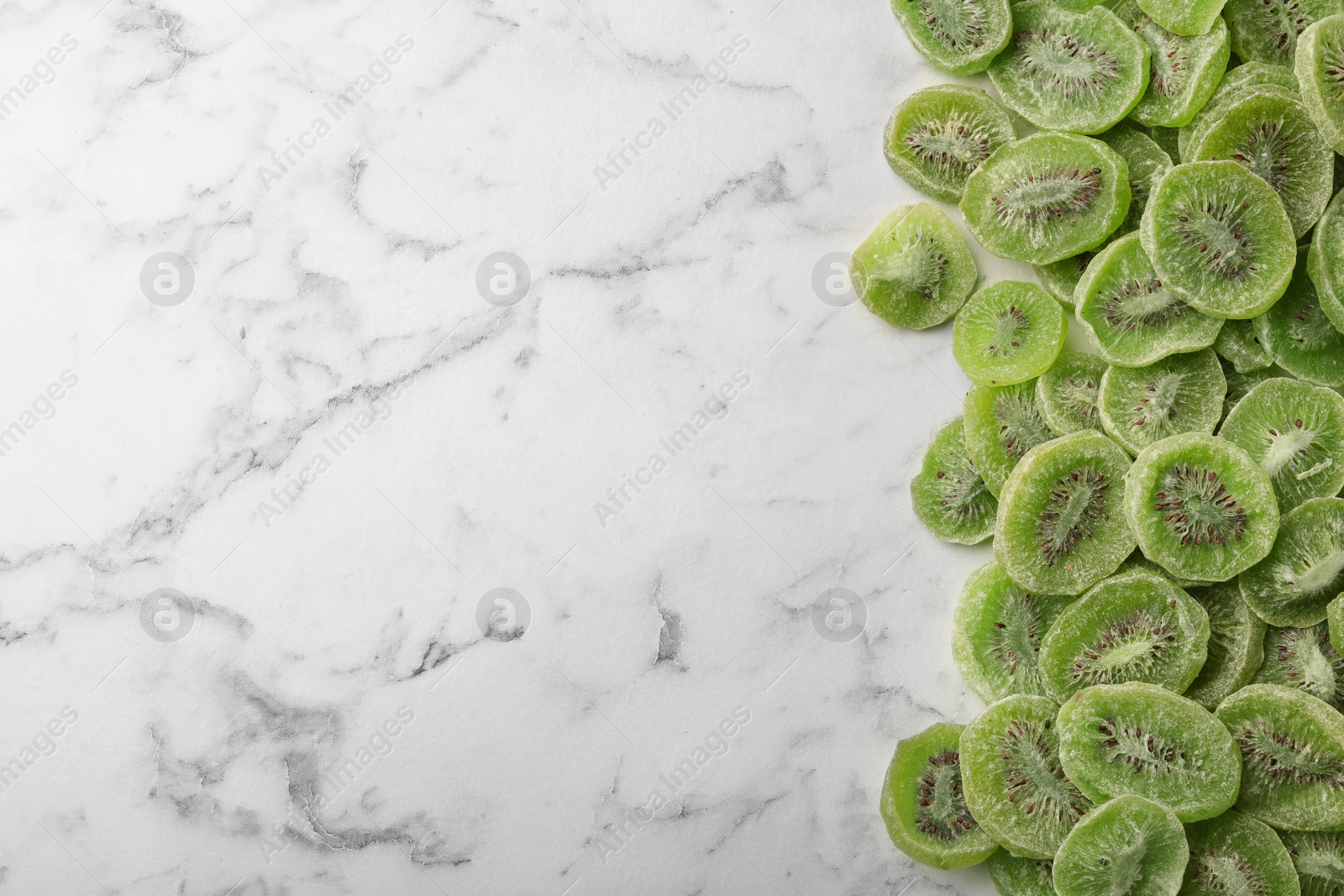 Photo of Slices of kiwi on marble background, top view with space for text. Dried fruit as healthy food