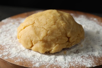 Photo of Making shortcrust pastry. Raw dough and flour on board, closeup