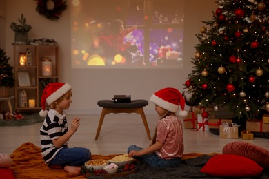 Photo of Brother and sister spending time together near video projector in room. Christmas atmosphere