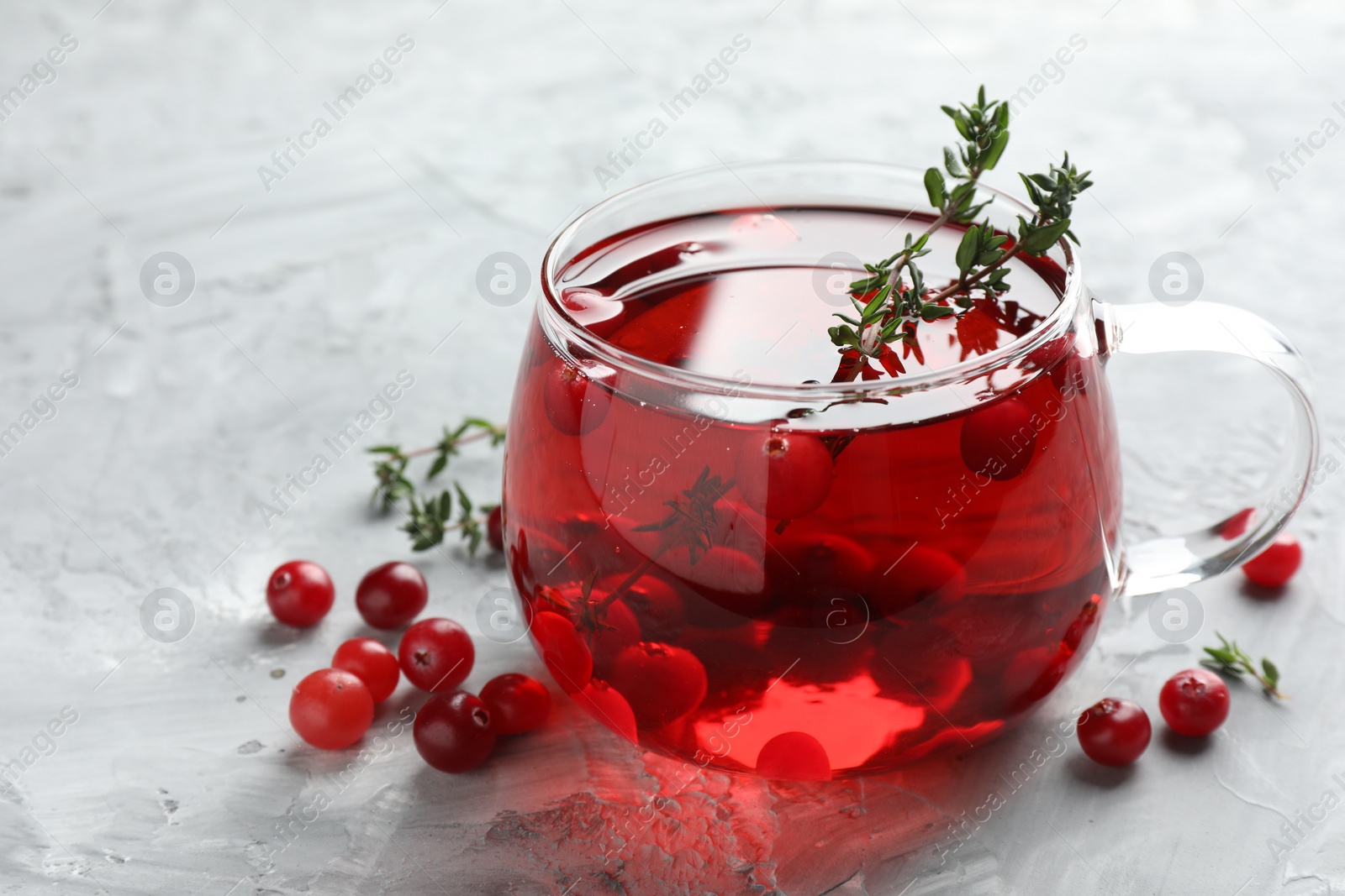 Photo of Delicious cranberry tea with thyme and berries on grey table, closeup