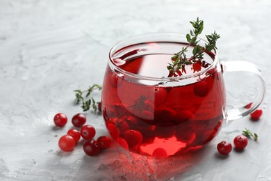 Photo of Delicious cranberry tea with thyme and berries on grey table, closeup