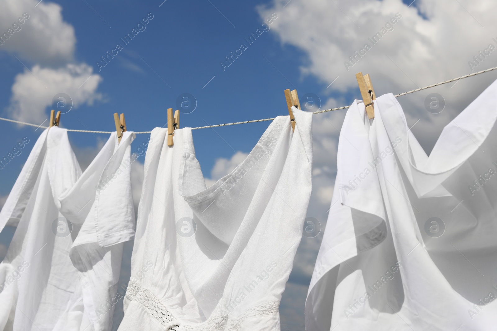 Photo of Clean clothes hanging on washing line against sky. Drying laundry