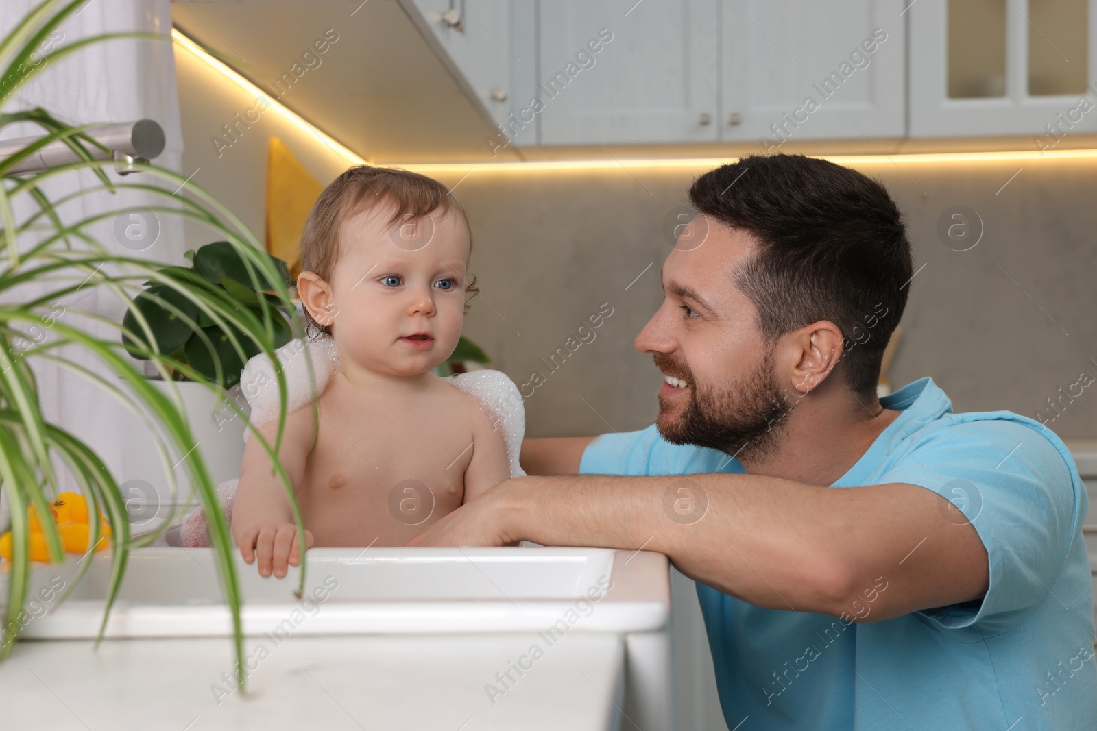 Photo of Father washing his little baby in sink at home