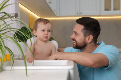 Father washing his little baby in sink at home