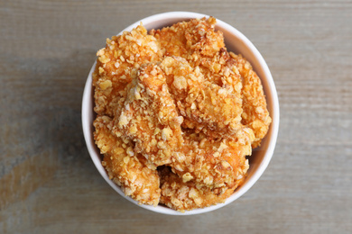 Photo of Bucket with yummy nuggets on wooden table, top view