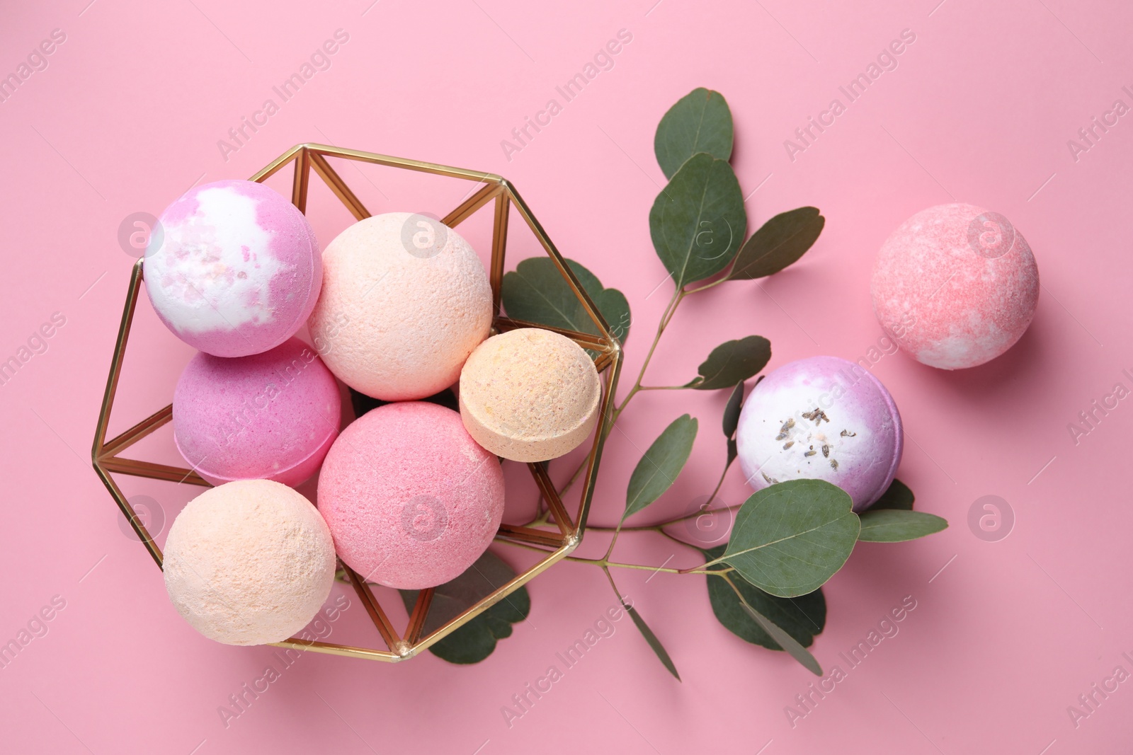 Photo of Bowl with bath bombs and eucalyptus leaves on pink background, flat lay