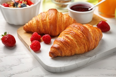 Photo of Tasty breakfast with croissants served on white wooden table, closeup