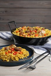 Photo of Delicious pilaf with meat, carrot and chili pepper served on wooden table