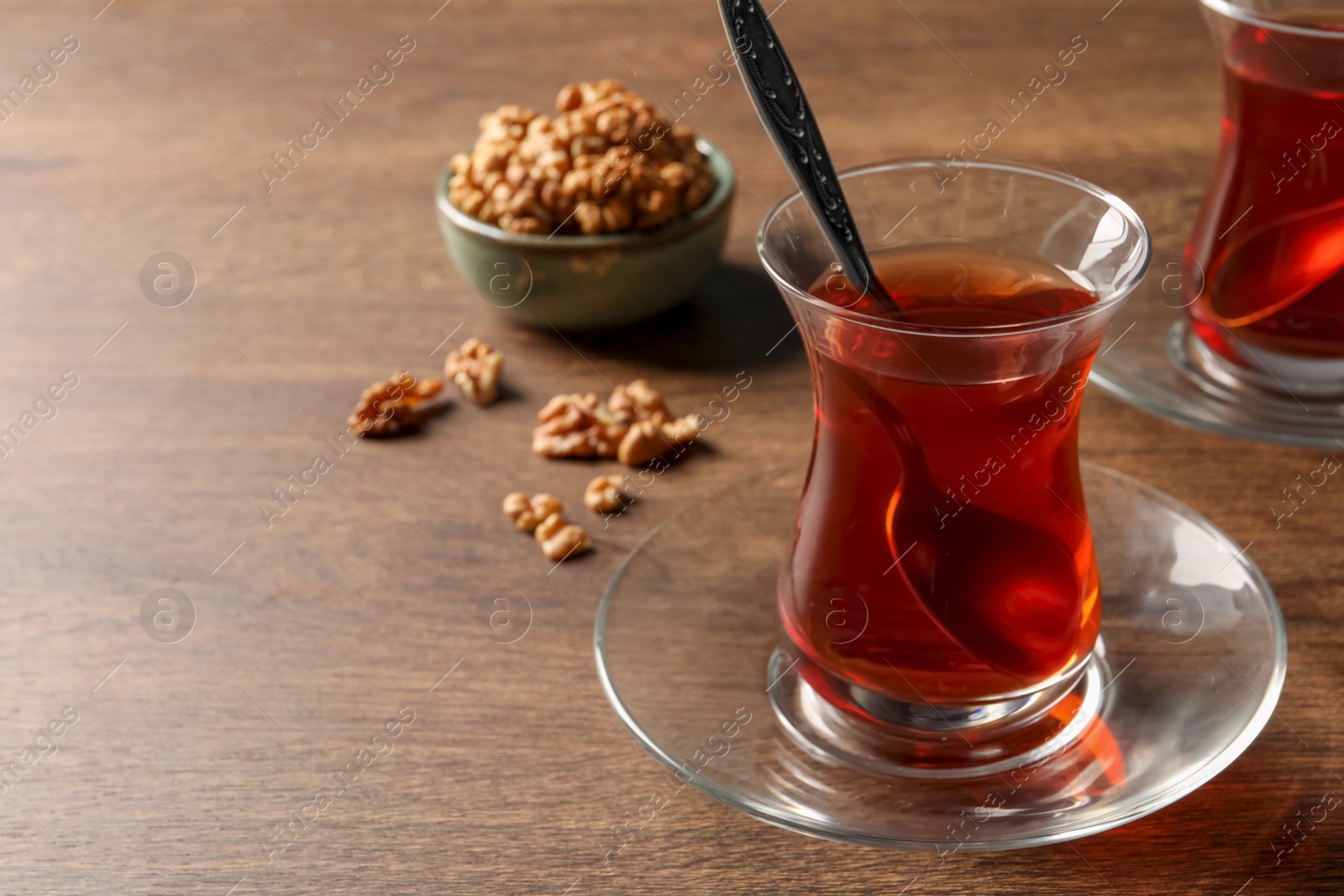 Photo of Glasses of traditional Turkish tea and walnuts on wooden table, closeup. Space for text