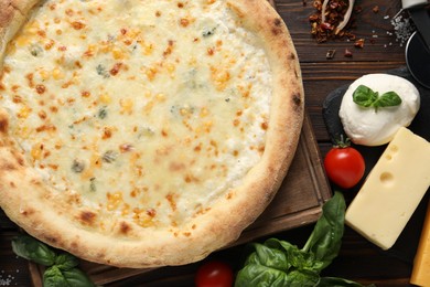 Photo of Delicious cheese pizza and ingredients on wooden table, flat lay