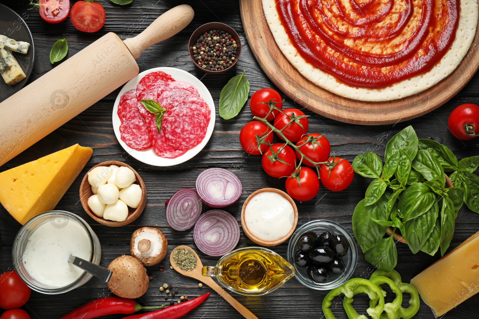 Photo of Flat lay composition with pizza crust and ingredients on dark wooden table