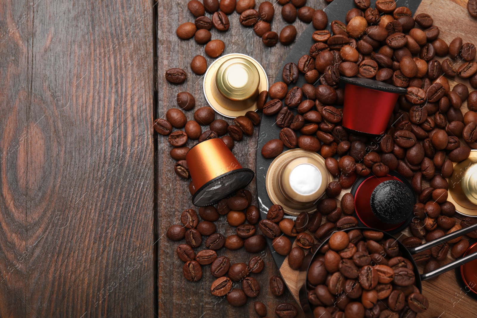 Photo of Saucepan with coffee capsules and beans on wooden table, flat lay. Space for text