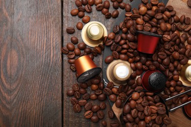 Photo of Saucepan with coffee capsules and beans on wooden table, flat lay. Space for text