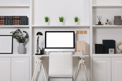 Photo of Cozy workspace with computer, lamp and stationery on wooden desk at home