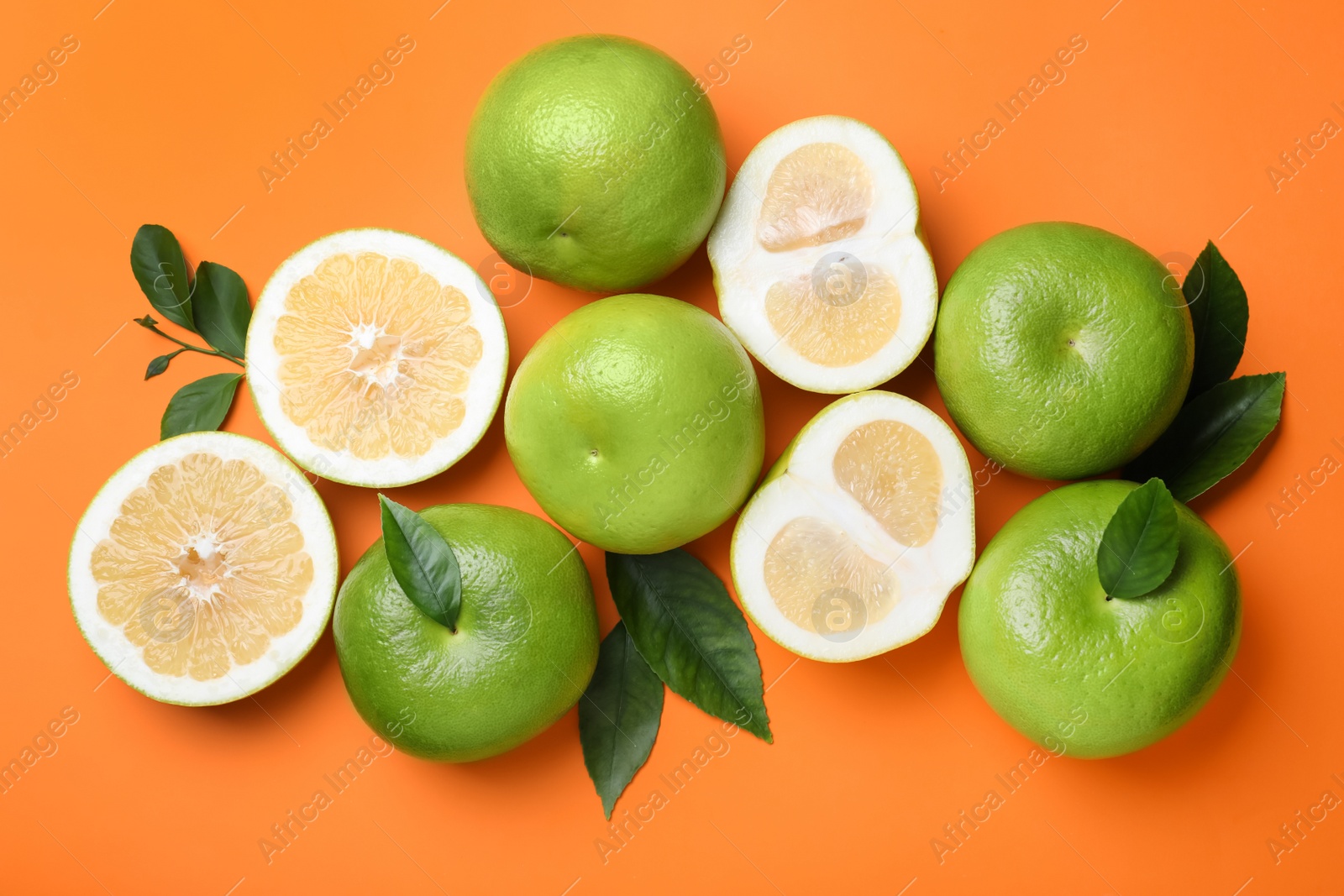 Photo of Fresh ripe sweeties and green leaves on orange background, flat lay