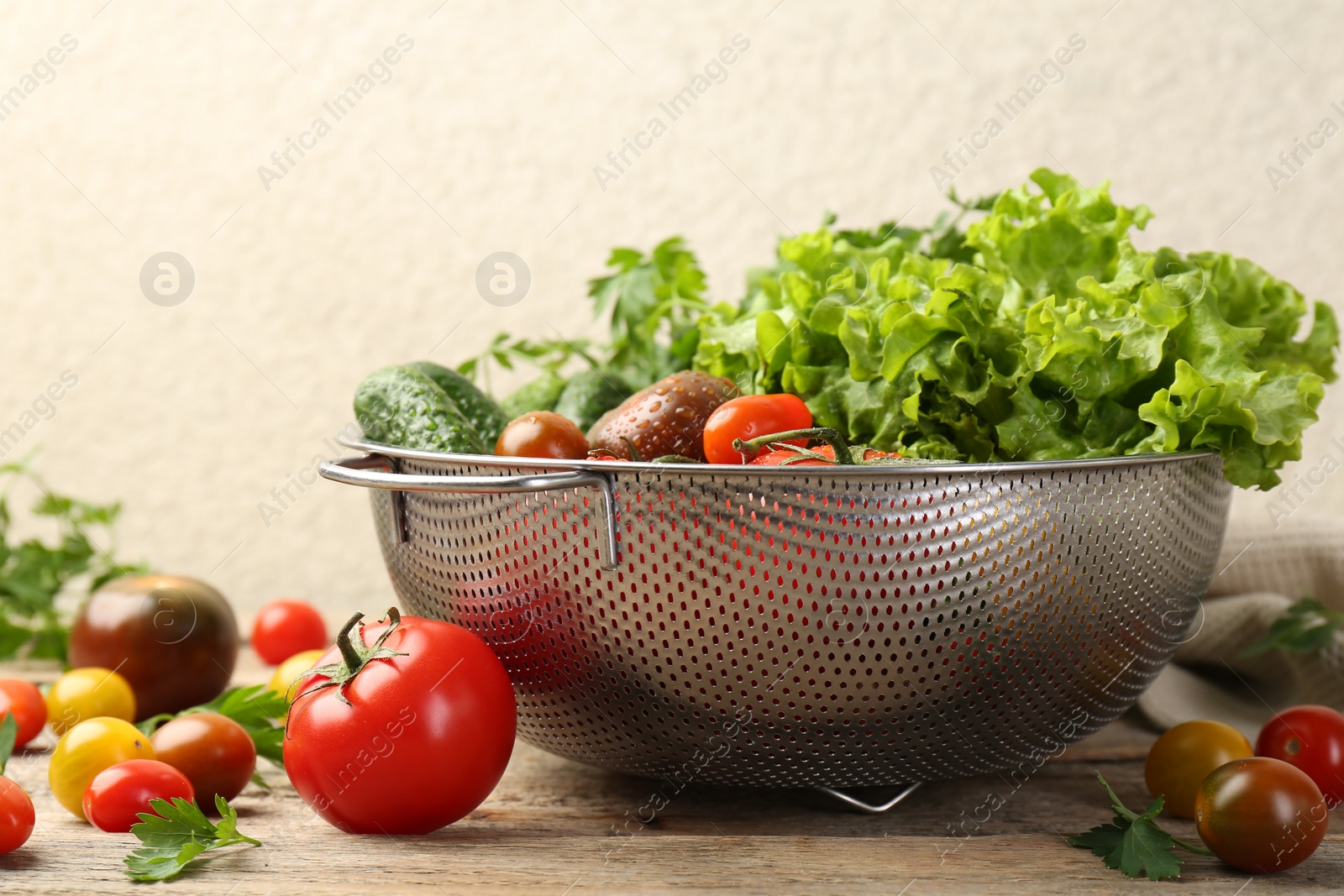 Photo of Wet vegetables in colander on wooden table, closeup