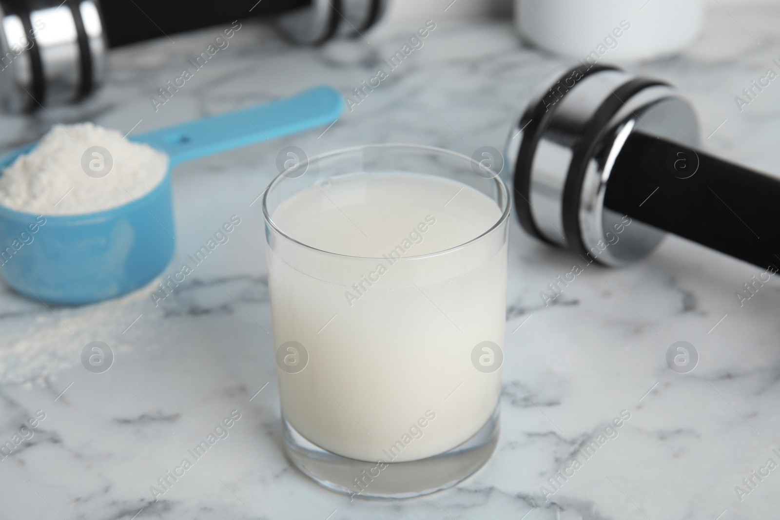 Photo of Amino acid shake, powder and dumbbells on white marble table