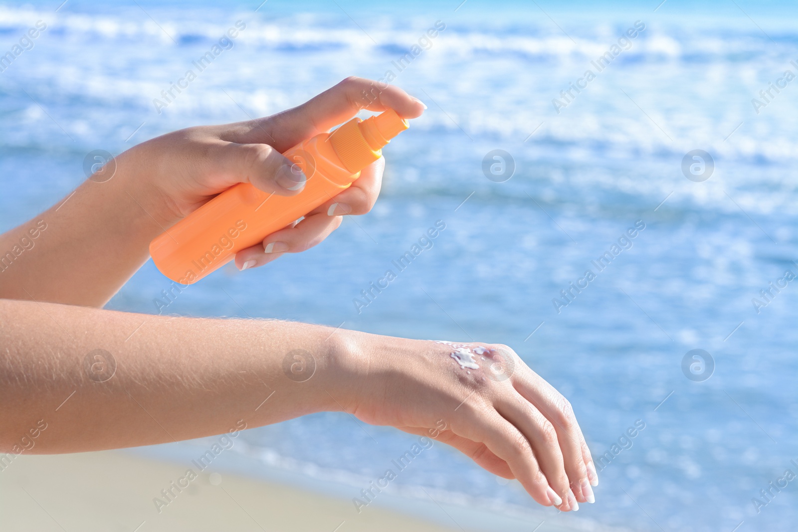 Photo of Woman applying sun protection cream on her hand at beach, closeup