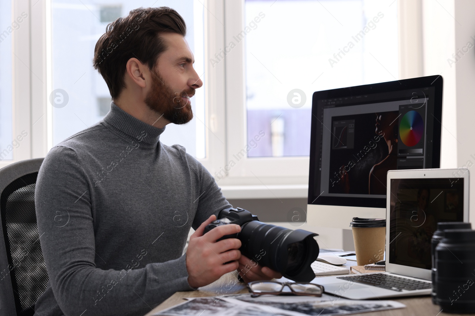 Photo of Professional photographer with digital camera at table in office