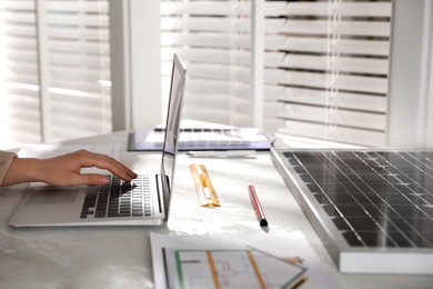 Photo of Woman working on project with solar panels at table in office, closeup