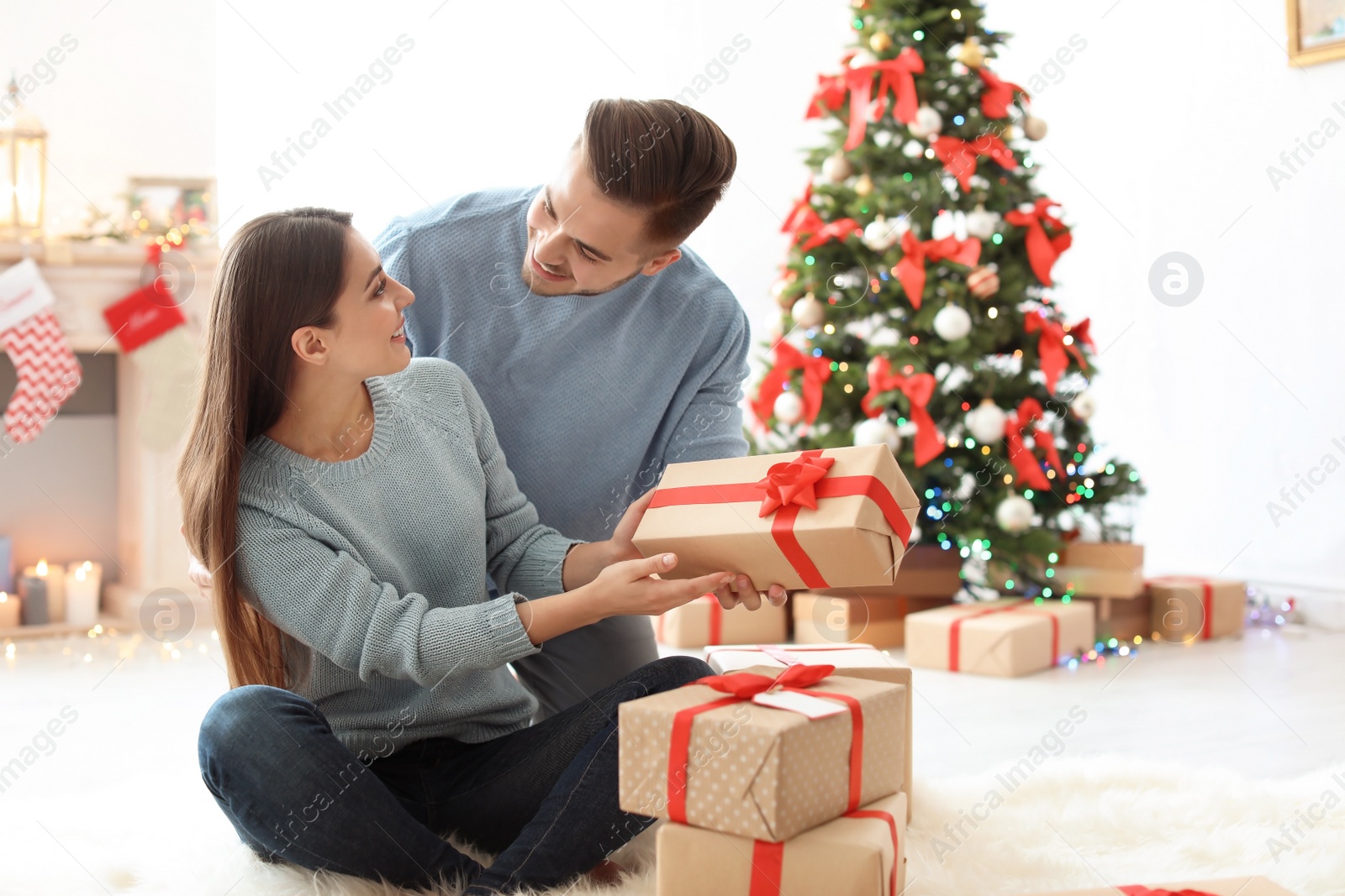 Photo of Young man giving Christmas gift to his girlfriend at home