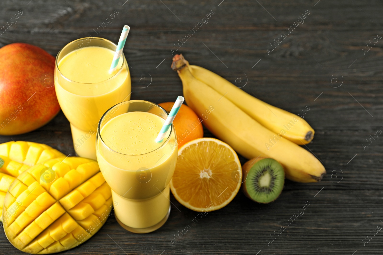 Photo of Tasty tropical drink with mango and fresh fruits on wooden table