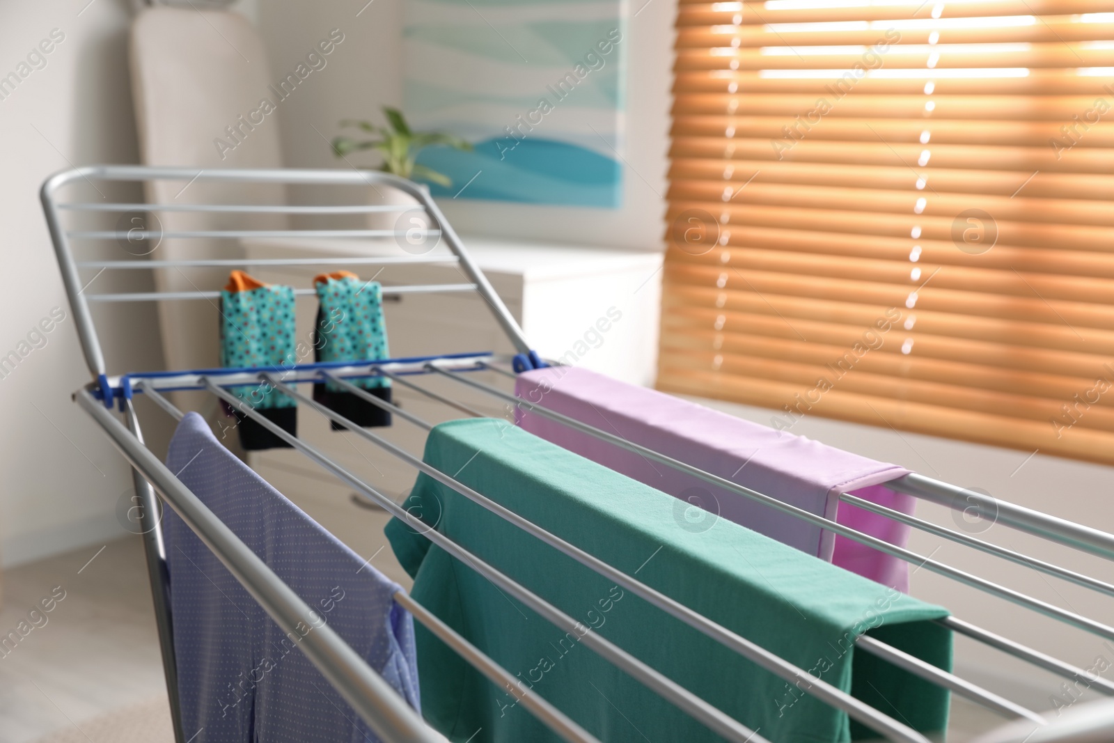 Photo of Clean laundry hanging on drying rack indoors, closeup