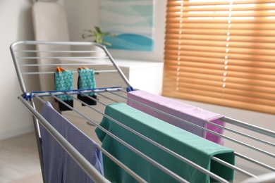 Clean laundry hanging on drying rack indoors, closeup