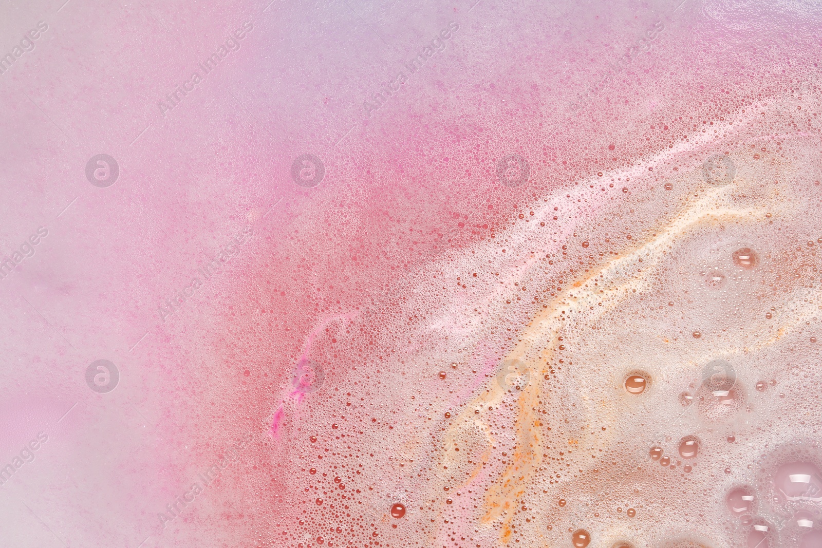 Photo of Colorful foam after dissolving bath bomb in water, closeup