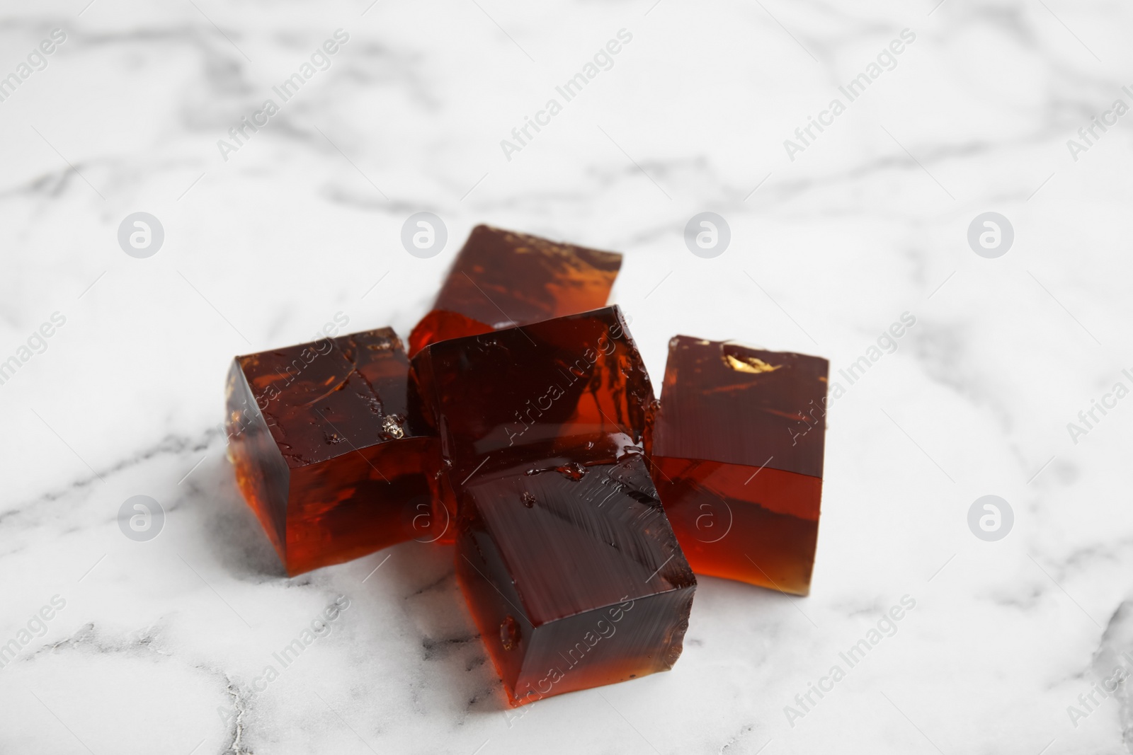 Photo of Heap of delicious grass jelly cubes on white marble table, closeup