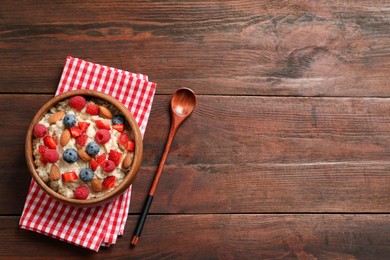 Tasty oatmeal porridge with berries and almond nuts served on wooden table, flat lay. Space for text