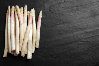 Photo of Fresh white asparagus on black table, flat lay. Space for text